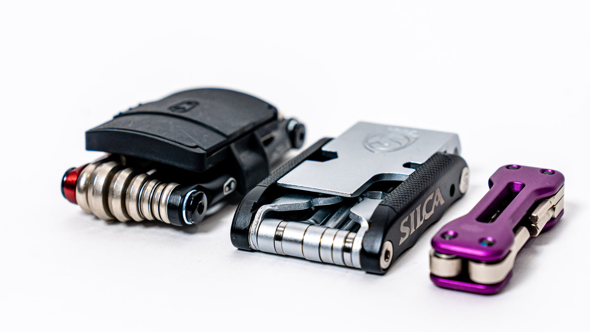 Three bike multi-tools, including a Silca tool, lined up on a white table