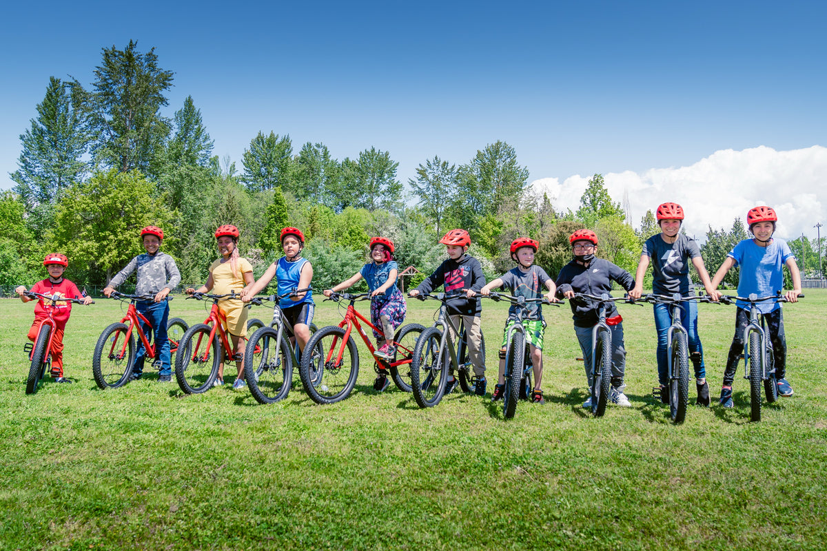Kids lined up with their new bikes at a Dialed Cycling Team Bikes for Kids event