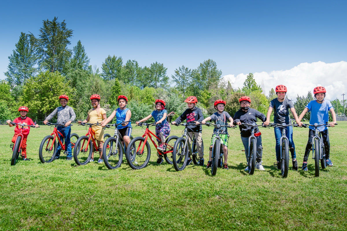 Kids lined up with their new bikes at a Dialed Cycling Team Bikes for Kids event